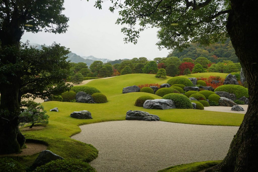 Jardín japonés exuberante con arbustos y rocas cuidadosamente podados.